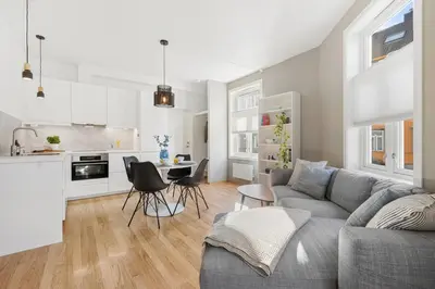 a living room with a gray couch and a kitchen at Central 3-room apartment in Trondheim