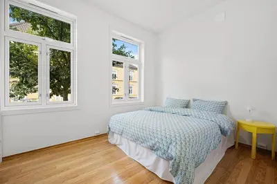 a white bedroom with a bed and two windows at Central 3-room apartment in Trondheim