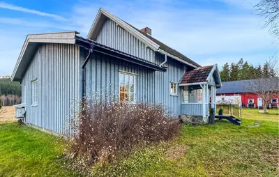 a blue house on a grass field with a red barn at Nice Home In Braskereidfoss With Wifi in Braskereidfoss