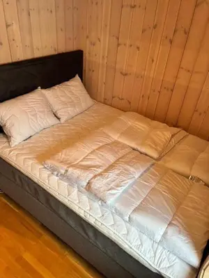 a bed with white sheets and pillows in a room at Ski-in & ski-out apartment in Hafjell in Øyer