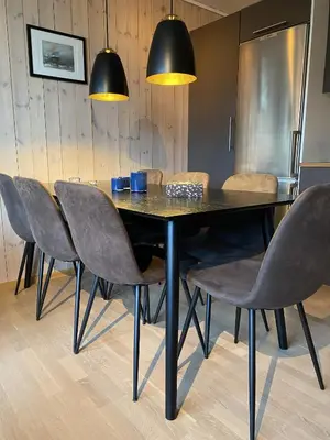 a black dining room table with chairs and lights at Ski-in & ski-out apartment in Hafjell in Øyer