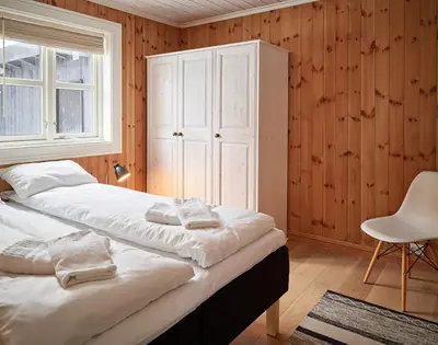 a bedroom with two beds and a cabinet and a chair at Stranda Fjellgrend 2 bedrooms - 35c in Stranda