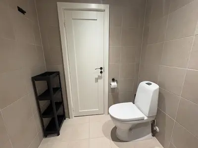 a bathroom with a white toilet and a door at Central apartment - walking distance to everything in Holo