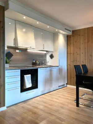 a kitchen with white cabinets and a table with chairs at Apartment in Gol Skisenter in Gol