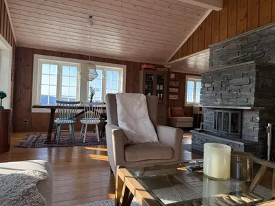 a living room with a stone fireplace and a table at Rustik hytte i Gausta, ski in, ski out, 10 beds in Gaustablikk