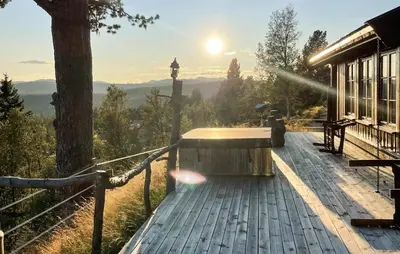 a hot tub on a deck with the sun in the background at Stunning Home In Austbygda With Wifi in Austbygdi