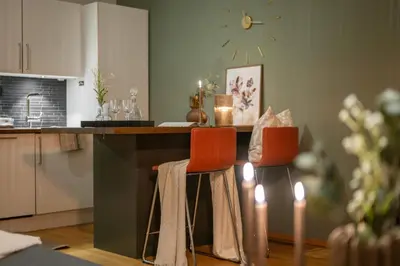 a kitchen with a counter with two orange chairs at Midtbyen Apartment in Trondheim