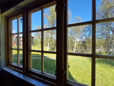 a window view of a yard from a house at Trivelig og romslig hytte nær Røros, rikelig med uteplass in Glåmos