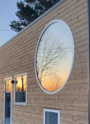 a large circular mirror on the side of a building at Tiny house on wheels with great views Sjusjøen in Mesnali