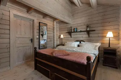 a bedroom with a bed and a wooden wall at Timber Cabin With Panoramic Views At Spåtind in Etnedal