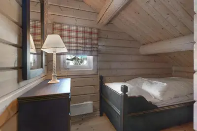 a bedroom with a bed and a desk with a lamp at Timber Cabin With Panoramic Views At Spåtind in Etnedal