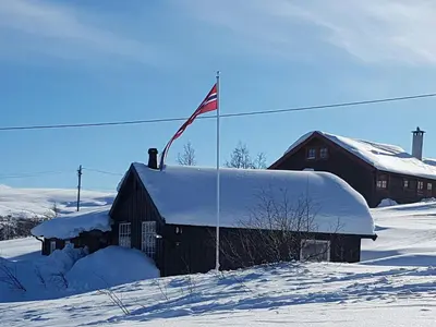 a building covered in snow with a flag on it at Family Cabin Near Rallarvegen And Geilo in Ustaoset