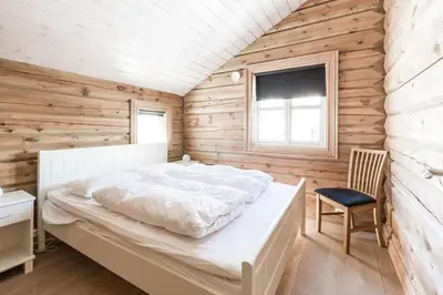 a bedroom with a white bed and a wooden wall at Stranda Fjellgrend 3 bedrooms - 68B in Stranda
