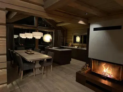 a dining room with a fireplace and a table and chairs at New exclusive cabin - panoramic view with ski in-out, Kvitfjell Varden in Ringebu