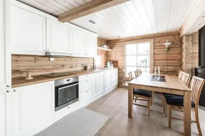 a kitchen with white cabinets and a wooden table at Stranda Fjellgrend 3 bedrooms - 68A in Stranda