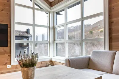 a living room with a table and large windows at Stranda Fjellgrend 3 bedrooms and loft - 80C in Stranda
