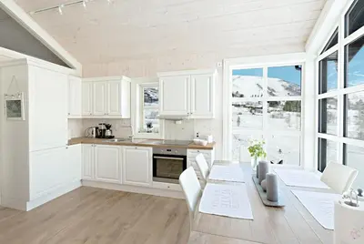 a kitchen with white cabinets and a table with chairs at Stranda Fjellgrend 2 bedrooms and loft - 30B in Stranda