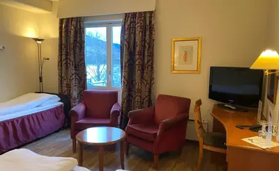 a hotel room with a bed and two chairs and a television at Park Hotel Vossevangen in Vossevangen