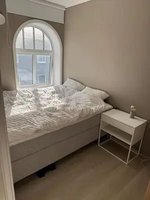 a bedroom with a bed and an arch window at Bright and modern city center apartment in Ålesund