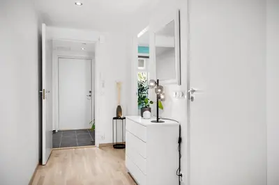 a white hallway with a white dresser and a mirror at Modern apartment by the sea - Free parking in Bergen