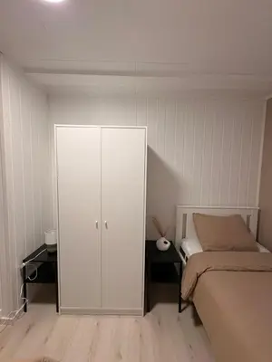 a bedroom with a white cabinet next to a bed at Kirkevegen apartment in Brumunddalen