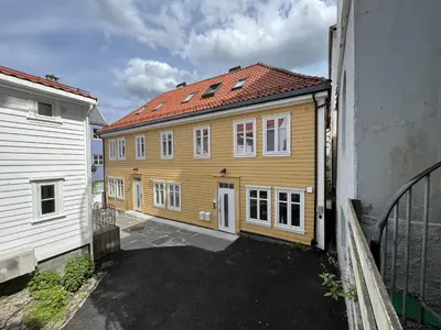 a yellow house with a red roof next to a building at Exclusive top apartment, central location in Bergen in Bergen