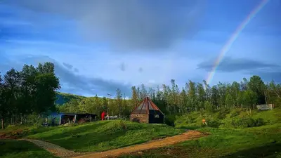 a rainbow in the sky over a field with a barn at Hessdalen Ufocamp in Vårhus