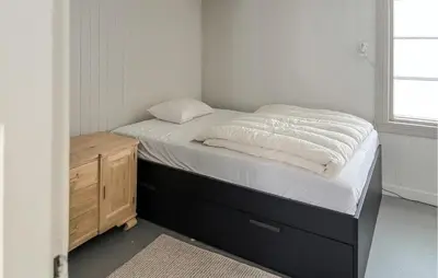 a small bedroom with a bed and a wooden dresser at Cozy Home In Oppdal With House A Mountain View in Oppdal
