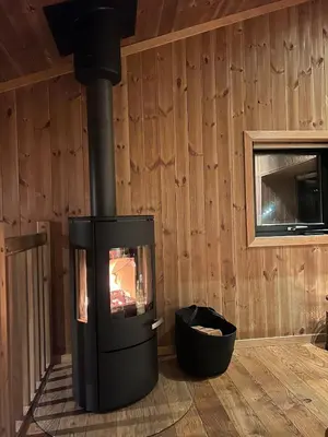 a fireplace in a room with a wooden wall at Charming and modern ski-in ski-out cottage in Hemsedal