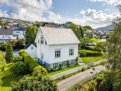a white house on the side of a road at Lundenhuset 1917 - historic house in the heart of Ulsteinvik in Ulstein