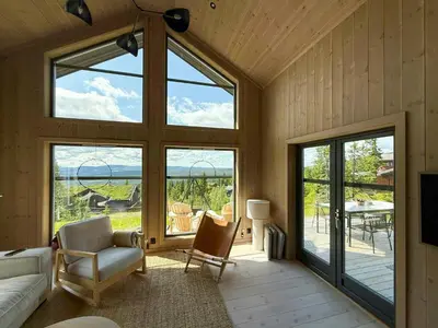 a living room with large windows and a couch and chairs at Modern Cabin With Ski-Inout Near Birken Trails in Rena