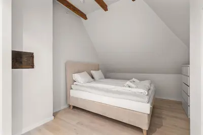 a bed in a room with white walls and wooden floors at Elegant Historic Villa - Stunning Views in Bergen
