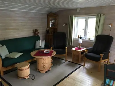 a living room with a green couch and two chairs at Øyungen 2 in Namsos