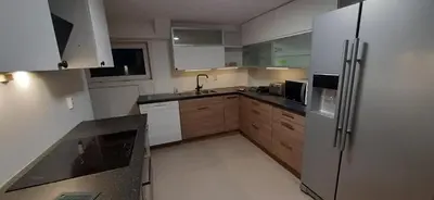 a kitchen with white cabinets and a stainless steel refrigerator at Rooms in easy accessible new apartment near Stave church in Bergen