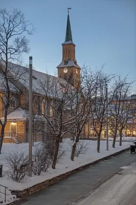 a building with a clock tower in the snow at Tromsø Apartment - in the heart of the city in Lii