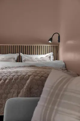a bedroom with two beds and a lamp on the wall at Tromsø Apartment - in the heart of the city in Lii