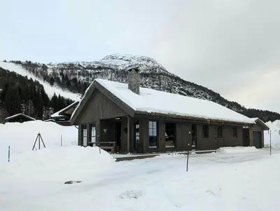 a cabin in the snow with a mountain in the background at Cabin With Ski Inout Near Stryn Alpine Resort in Stryn