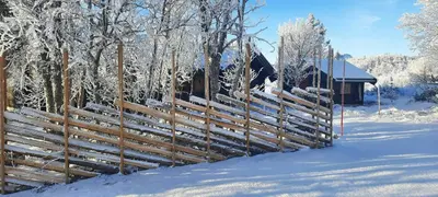 a wooden fence in the snow next to a cabin at Log Cabin Near Muen And Myafallene in Venabygd