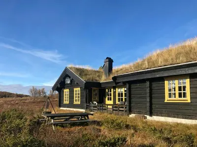 a house with a grass roof with a picnic table in front of it at Log Cabin Near Muen And Myafallene in Venabygd
