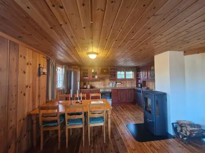 a kitchen with a table and chairs and a wooden ceiling at Fjellvang in Haglebu