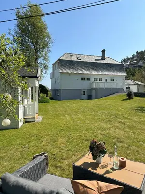 a backyard with a table and a large building at Spacious Group Villa with Jacuzzi and Views in Askøy