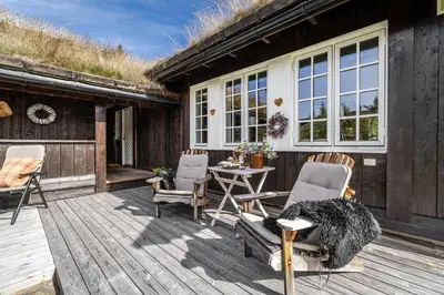 a patio with chairs and a table on a wooden deck at Charming cabin in Hemsedal Golf Alpin - ideal for families, fishing & skiing in Hemsedal