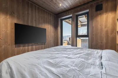 a bedroom with a bed with a television on the wall at New luxury cabin in Geilo with hot tub, mountain views & ski access in Geilo