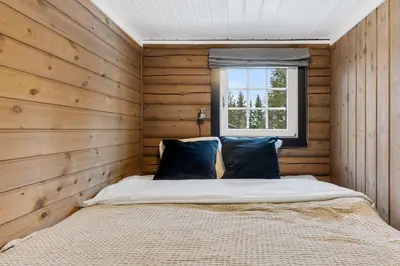 a bedroom with wooden walls and a bed with a window at Vikinggrenda 16A by Vacation Trysil in Trysil