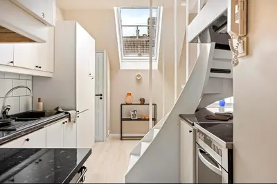 a kitchen with white cabinets and black counter tops at Koselig bygårdsleilighet i Bergen sentrum in Bergen