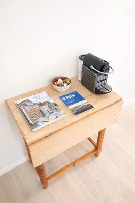 a wooden table with a printer and magazines on it at Koselig bygårdsleilighet i Bergen sentrum in Bergen