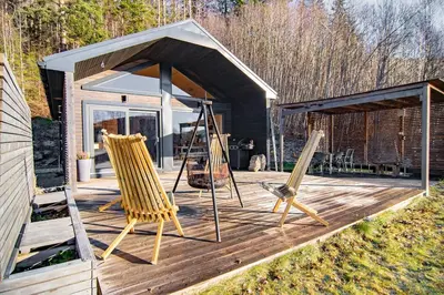 a wooden deck with two chairs and a shed at Unique Nature Hideaway Close to Norefjell