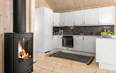 a fireplace in a kitchen with white cabinets at 3 Bedroom Gorgeous Home In Nesbyen in Nesbyen