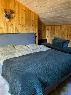 a bedroom with a large bed with wooden walls at Cabin With Ski Inout Near Gribbe, Valdres in Tisleidalen