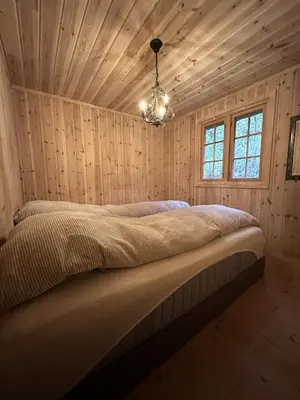 a bed in a room with wooden walls and a chandelier at Family cabin in Hafjell, ski in-ski out in Hafjell